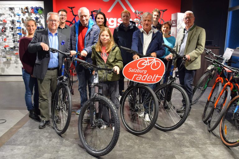Gruppe von Personen mit Fahrrädern und „Salzburg radelt“-Schild bei der Preisübergabe.
