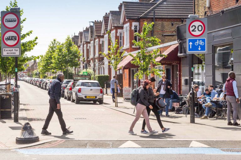 Stadtstraße mit Radweg, Fußgängern, Tempo-20-Zone und Straßencafés