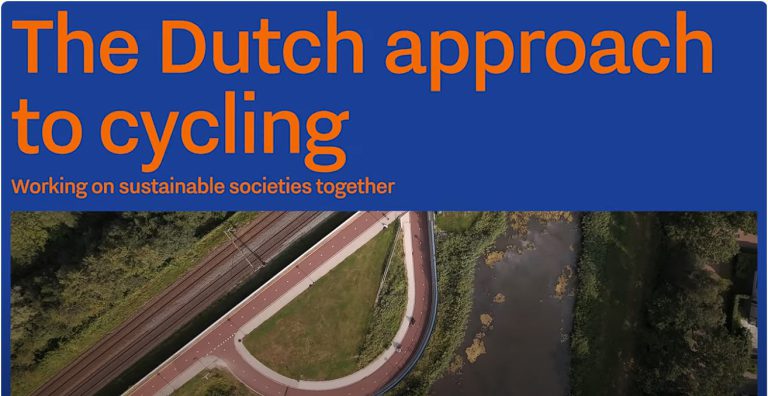 Luftaufnahme Radweg mit Kurve neben Bahngleisen und Wasser in grüner Landschaft