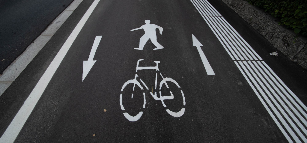 Fahrradweg und Gehweg Markierung mit Richtungspfeilen und Bodenleitsystem für Blinde