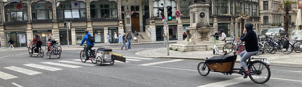 Mehrere Radfahrende mit Lastenrädern und Anhängern im Stadtverkehr