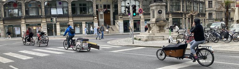 Mehrere Radfahrende mit Lastenrädern und Anhängern im Stadtverkehr