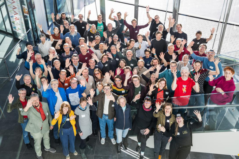 Gruppe von Menschen winkt in einem hellen Gebäude