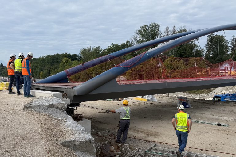 Arbeiter montieren neue Fahrradbrücke mit Stahlbögen