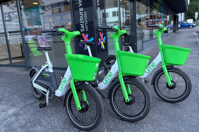 Drei grüne Lime-Leihräder geparkt vor dem Kundencenter des Salzburger Verkehrsverbunds