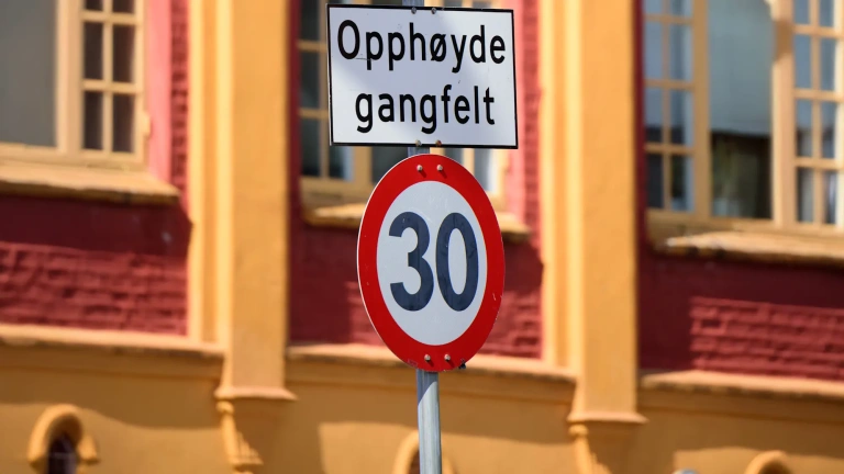 Tempo-30-Schild mit Hinweis „Opphøyde gangfelt“ vor einer gelb-roten Hausfassade